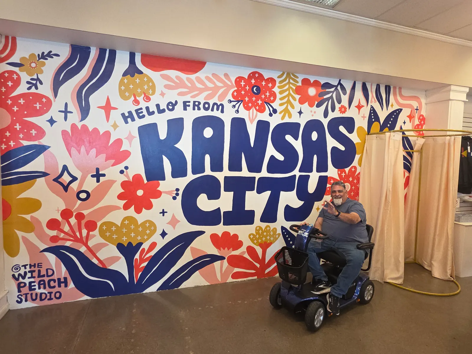 Rider on a mobility scooter rental at the Hello From Kansas City mural