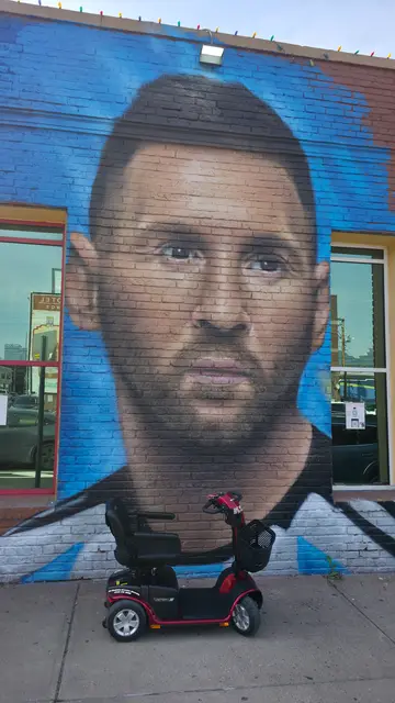 Mobility scooter from KC Mobility at a large face mural in Kansas City